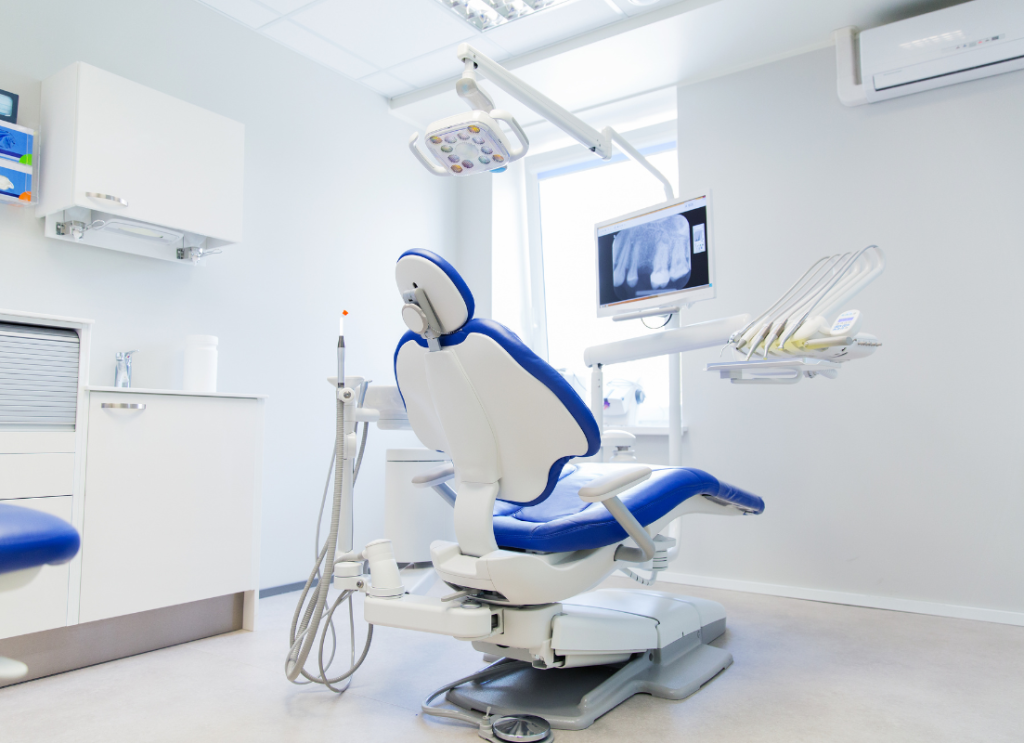 • Niebieski fotel stomatologiczny z monitorem diagnostycznym w jasnym gabinecie.