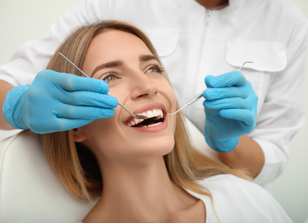 Uśmiechnięta blondynka na fotelu dentystycznym podczas badania kontrolnego zębów.